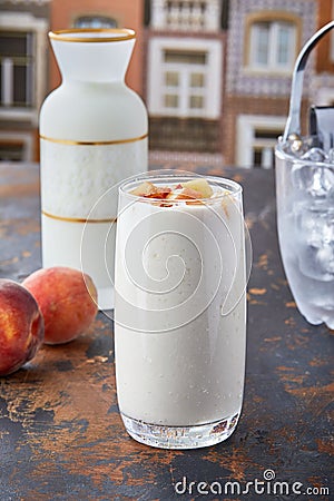 Vertical shot of a peach smoothie in big glass on the table with blur background Stock Photo