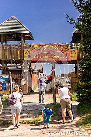 Vertical shot of people at the Western City park entrance with wooden towers and retro entry board. Editorial Stock Photo