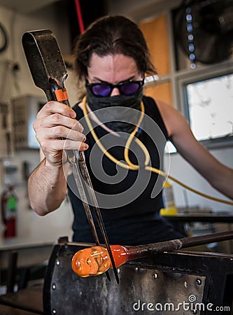 Vertical shot of a person glass blowing in the workshop Stock Photo