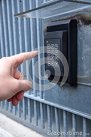 Vertical shot of a person ringing the gate intercom in the daylight Stock Photo