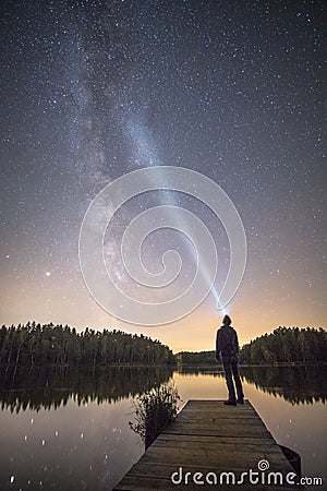 Vertical shot of a person standing on a boardwalk admiring the Milky Way and the starry night Stock Photo