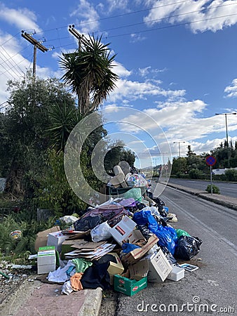 Vertical shot of a pile of rubbish and overflowing trash bins on the side of the road Editorial Stock Photo