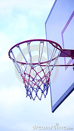 Vertical shot of a pink basketball hoop with a background of a cloudy sky Stock Photo