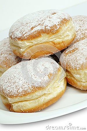 Vertical shot of powdered Berliner donuts on white plate Stock Photo