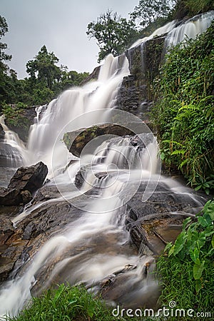 Vertical shot of raging waterfalls surrounded by trees Stock Photo