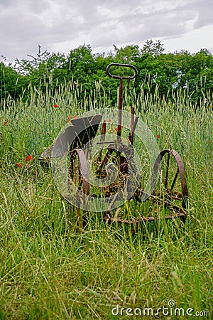 Vertical shot of rusty equipment in a grass field Stock Photo