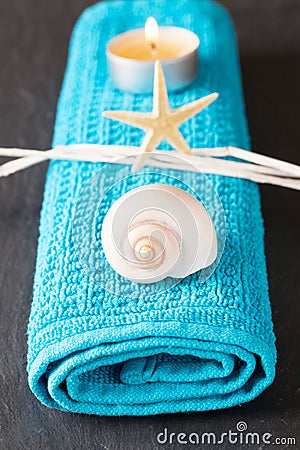 Vertical shot of a seashell, a seastar and a lit tea candle on a blue towel Stock Photo