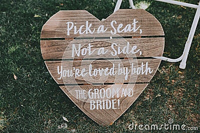 Vertical shot of signage, pick a seat either side on a wedding day with a blurred background. Stock Photo