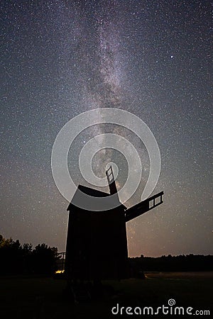 Vertical shot of the silhouette of a windmill under the Milky Way constellation at night Stock Photo