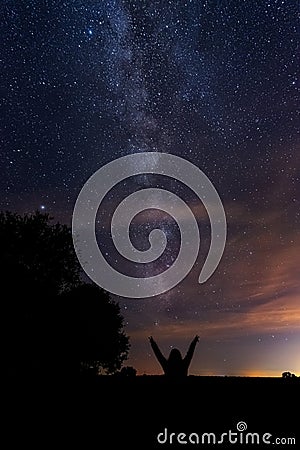 Vertical shot of silhouettes of a person pointing at the milky way in the night sky Stock Photo