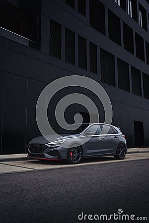 Vertical shot of a sleek gray sports car parked near a black building Editorial Stock Photo