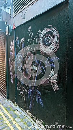 Vertical shot of small street with art graffiti flowers on a wall in Belfast city, United Kingdom Editorial Stock Photo