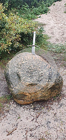 Vertical shot of a small sword in the stone on a sunny day Stock Photo