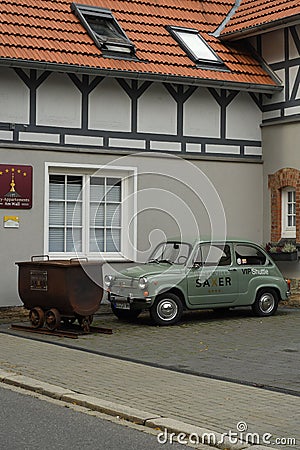 Vertical shot of a small vintage green FIAT 500 near a mining lorry in Goslar, Germany Editorial Stock Photo