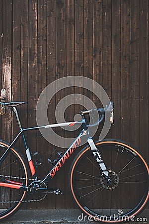 Vertical shot of a specialized Crux bicycle leaning on a wooden wall Editorial Stock Photo