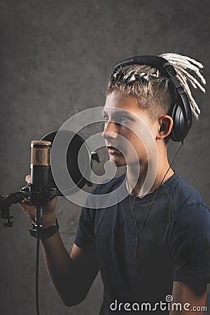 Vertical shot stilysh guy with dreadlocks is recording a song in the studio. A young attractive singer in black studio headphones Stock Photo