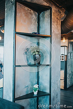 Vertical shot of a stylish metal shelf with flower pots in a modern interior Stock Photo