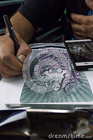 Vertical shot of a tattoo artist drawing a tattoo under the lights in a studio Editorial Stock Photo