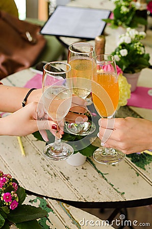 Vertical shot of three people holding glasses of alcohol over the table Stock Photo