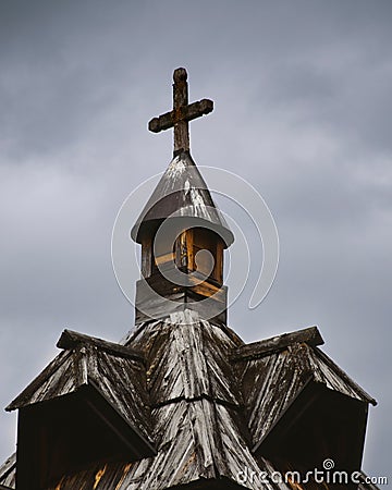 Vertical shot of a top part of a church covered in snow under a cloudy sky. Stock Photo