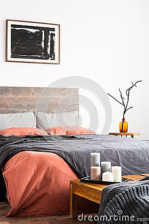 Shot of wooden bed with linen bedclothes, artwork and orange vase Stock Photo