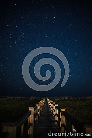 Vertical shot of a wooden path under the amazing Milky Way over Holden Beach, North Carolina Stock Photo