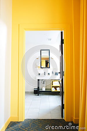 Vertical shot of the yellow wall with a bathroom visible through a doorway Editorial Stock Photo