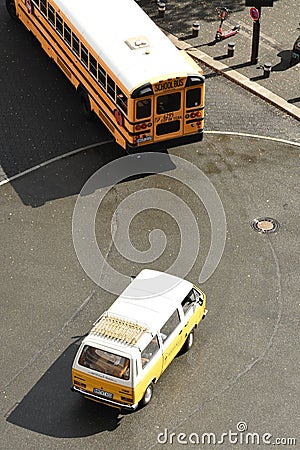 Vertical shot of a yellow and white automobile driving behind an American school bus on a roadway Editorial Stock Photo