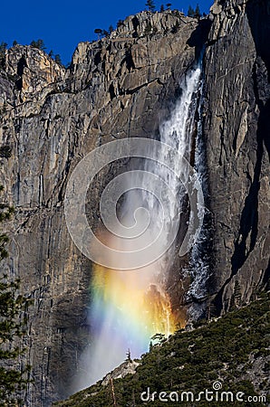 Vertical shot of the Yosemite Falls flowing with sunlight catching a rainbow Stock Photo