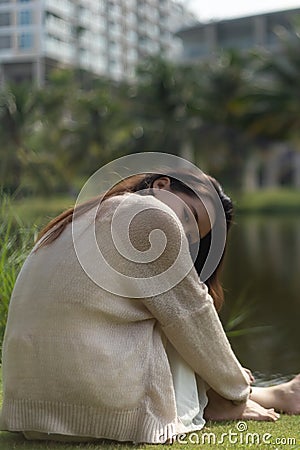 Vertical shot of a young Asian woman looking at the camera at the park Stock Photo