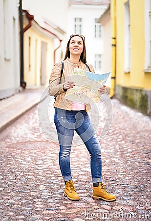 Vertical shot of young happy woman holding map. Stock Photo
