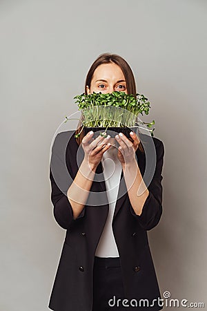 Vertical shot of a young woman holding micro greens saying be healthy. Stock Photo