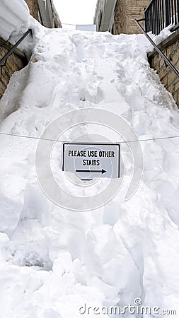 Vertical Snowed in stairway with sign that reads Please Use Other Stairs in winter Stock Photo