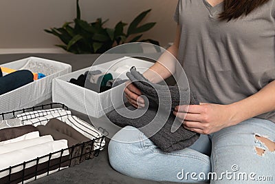 Vertical storage of clothing.Women organize clothes in a modern bedroom. Women sorting clothes in baskets room cleaning concept Stock Photo
