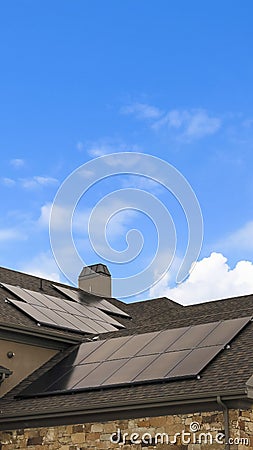Vertical tall frame Cloudy blue sky over a home with solar panels on the pitched roof Stock Photo