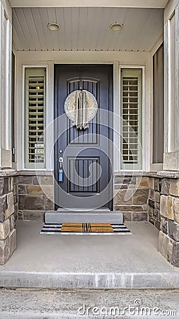 Vertical tall Home entrance with a gray front door in the middle of sidelights with blinds Stock Photo