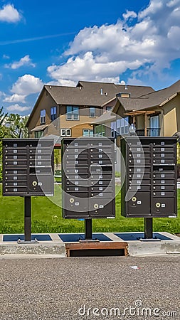 Vertical tall Row of cluster mailboxes with numbered compartments on the sidewalk Stock Photo