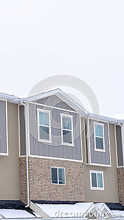 Vertical Upper storey of townhomes with snowy pitched roofs on a cold winter day Stock Photo