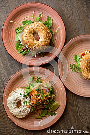 Vertical various delicious sesame donuts burgers with cheese, meat filling, greenery filling, sauce served up on plates Stock Photo