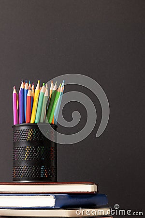 Vertical video of composition of crayons in container on stack of books on grey background Stock Photo