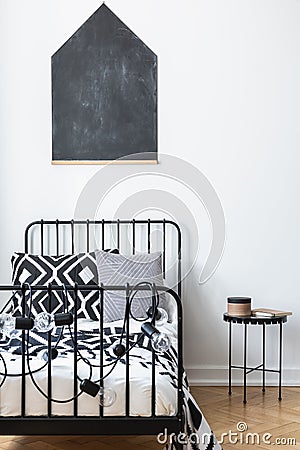 Blackboard on the wall of teenagers bedroom with black and white patterned bedding on single metal bed, real Stock Photo