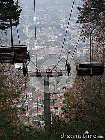 Vertical view of the empty cabins and wires of telecabin before the cityscape Stock Photo