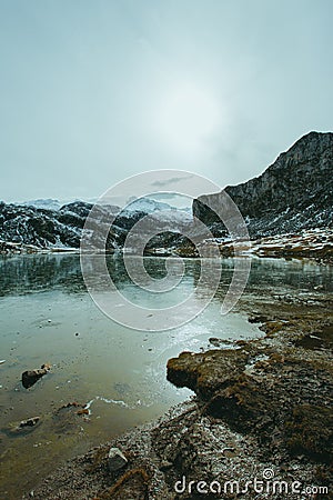 Vertical view of a frozen lake in front of a massive mountain with snow and copy space Stock Photo
