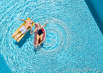 Vertical view of happy couple of old senior people enjoying the summer holiday vacation at the blue water pool with coloured treny Stock Photo