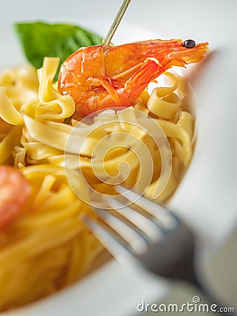 Vertical view to plate with pasta and shrimp with fork Stock Photo