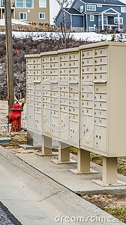 Vertical White metal cluster mailboxes and red fire hydrant along a concrete road Stock Photo
