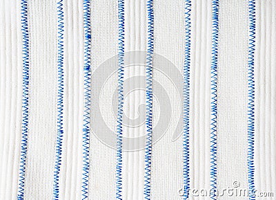 Vertical white stripes of two different fabrics are connected by a blue zigzag stitch. Stock Photo