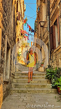 VERTICAL: Young female photographer wanders through the sunlit alleys in Korcula Stock Photo