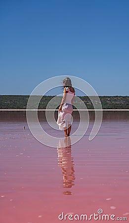 Vertical of a young female in a white dress standing in Pink Lake in Port Gregory, Australia Stock Photo