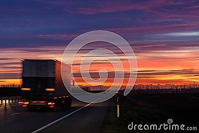 A very colorful sunset and a moving blurred truck on an asphalt road Stock Photo